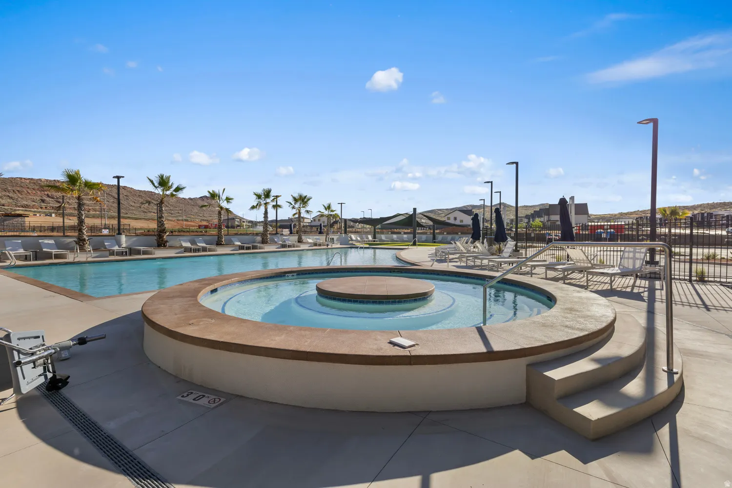 Resort-style pool and spa amenities featuring a circular hot tub with integrated seating, Olympic-length swimming pool, and expansive sundeck with lounge areas