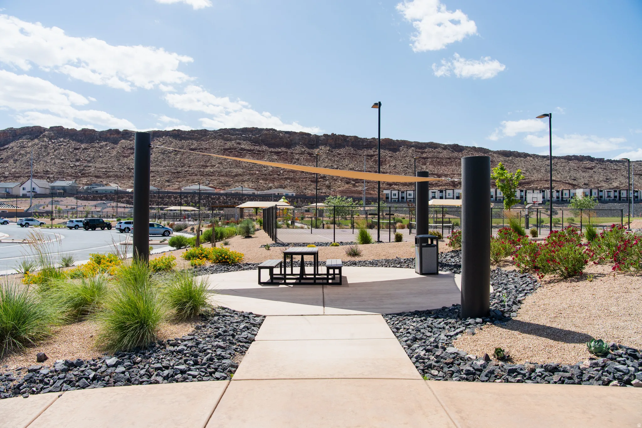 Outdoor amenity area featuring a concrete pathway, a shade sail structure, and a picnic table