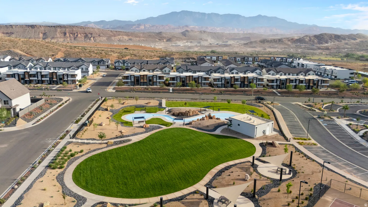 Community park featuring a green lawn, swimming pool, and shade structures