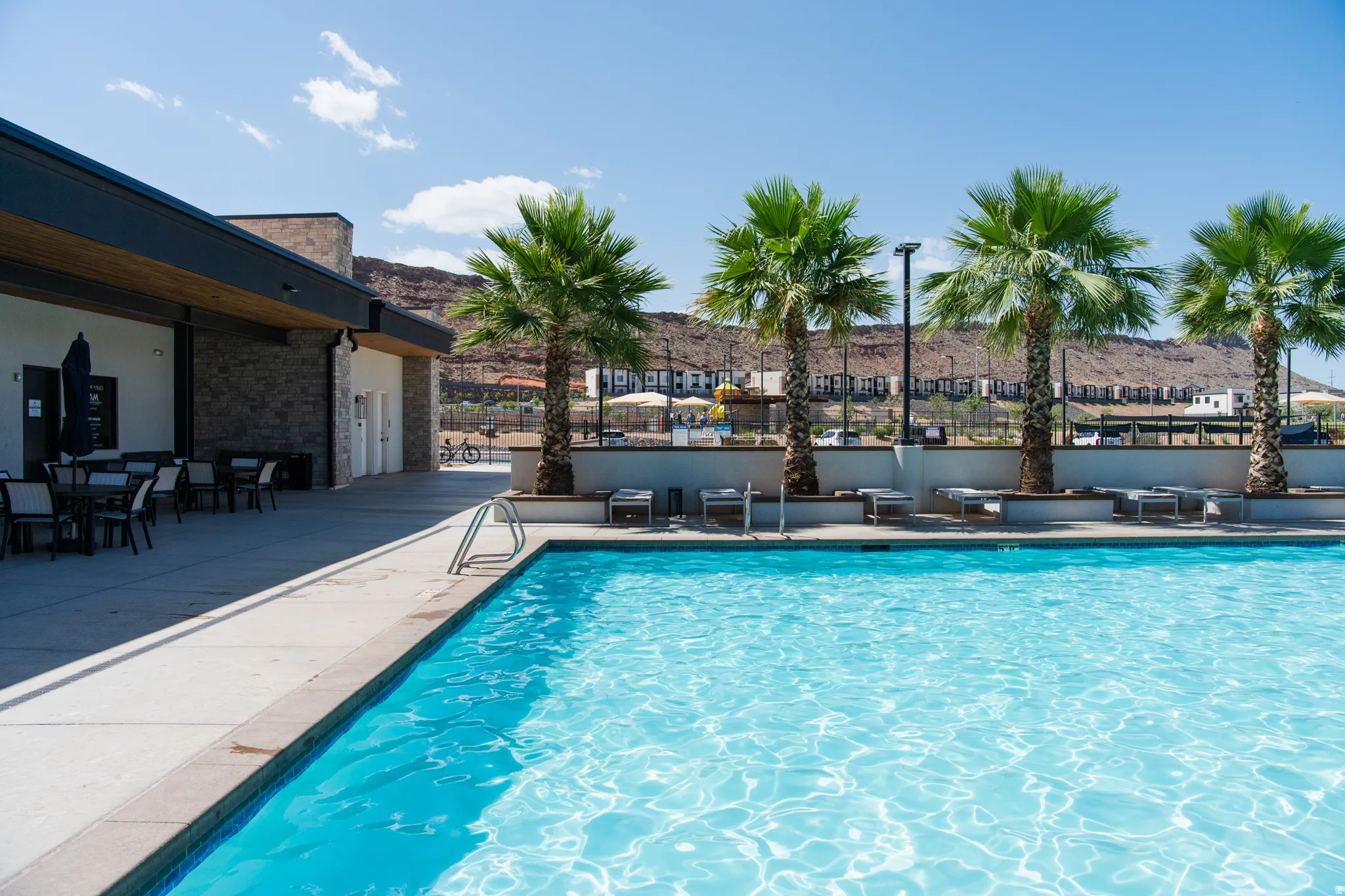 Expansive outdoor pool area featuring a blue-tiled swimming pool and surrounding concrete decking