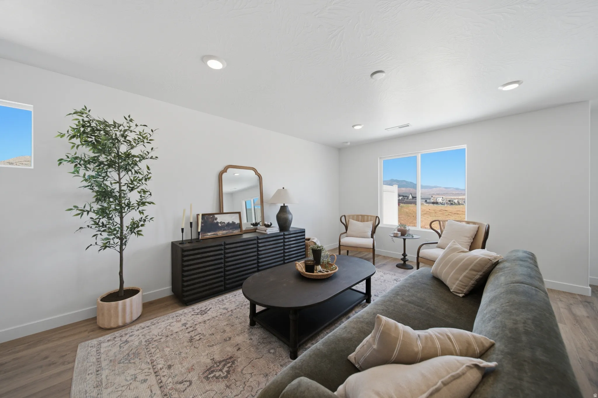 Bright living space featuring a large picture window, recessed lighting, and wood-finish flooring