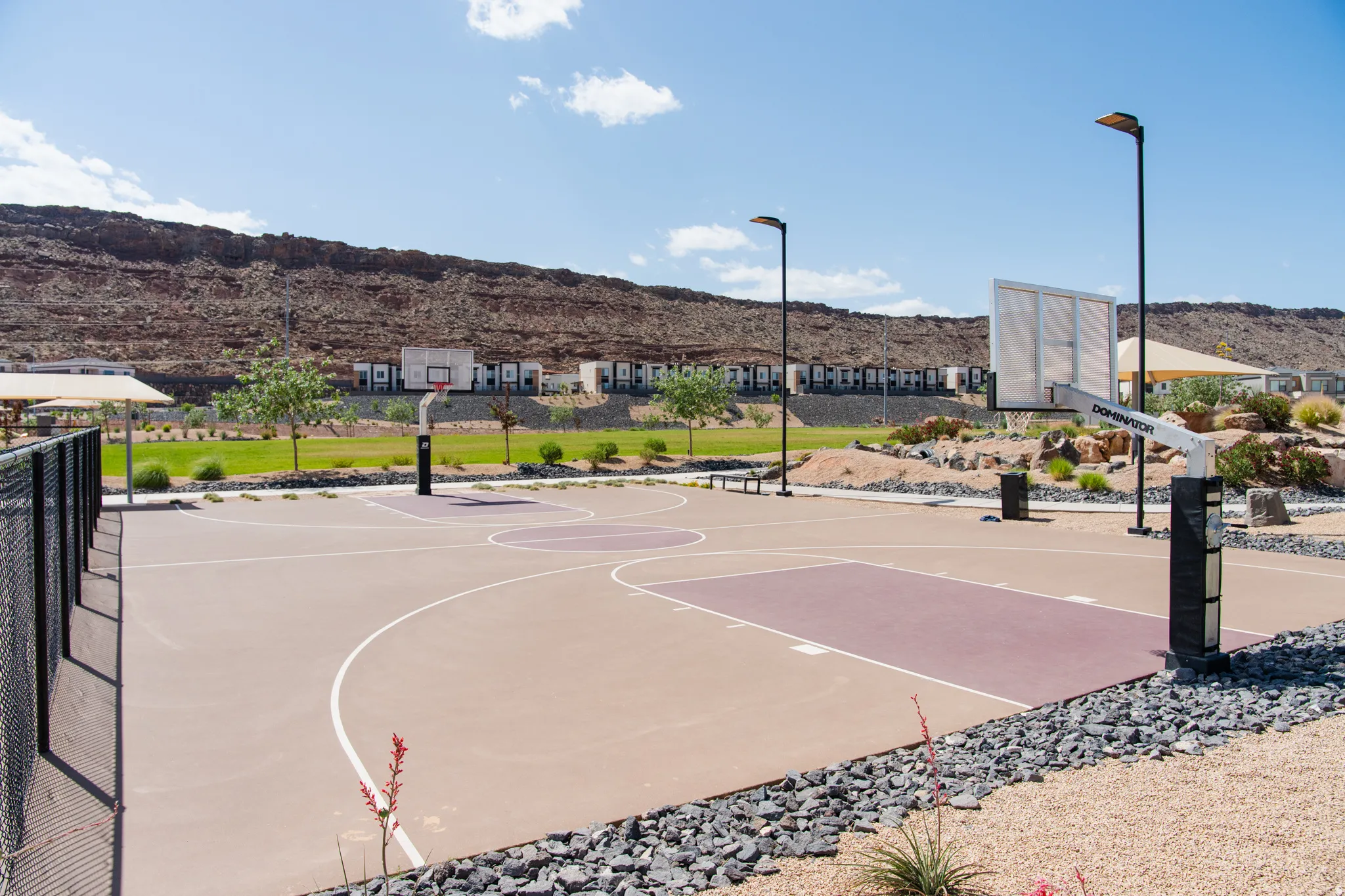 Outdoor basketball court featuring two hoops, court markings, and integrated lighting