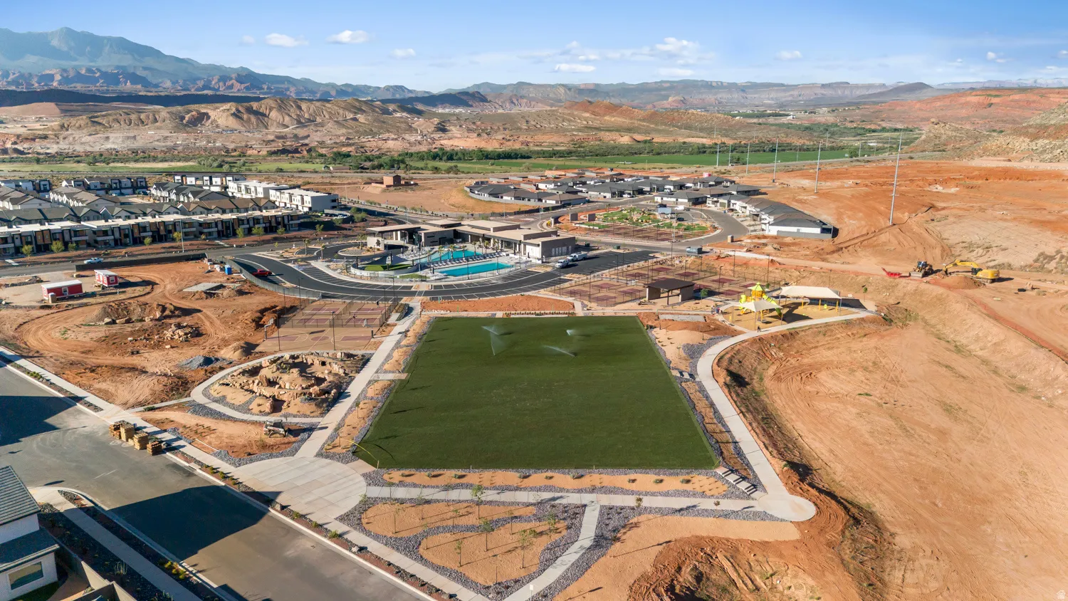 Expansive green space featuring an artificial turf field, surrounded by a paved walking path