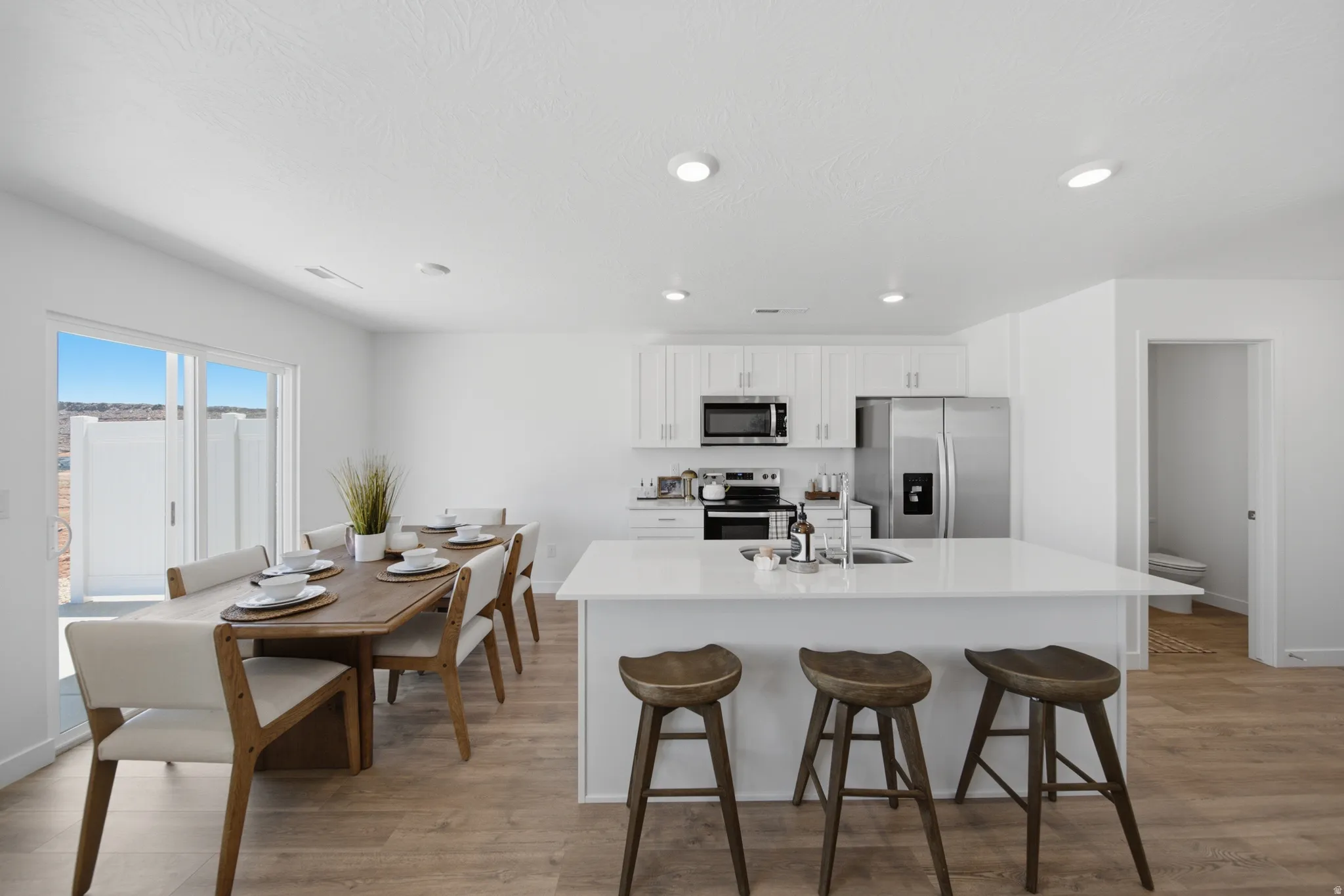Open-concept living space featuring wood-finish flooring, recessed lighting, and a modern kitchen with white cabinetry