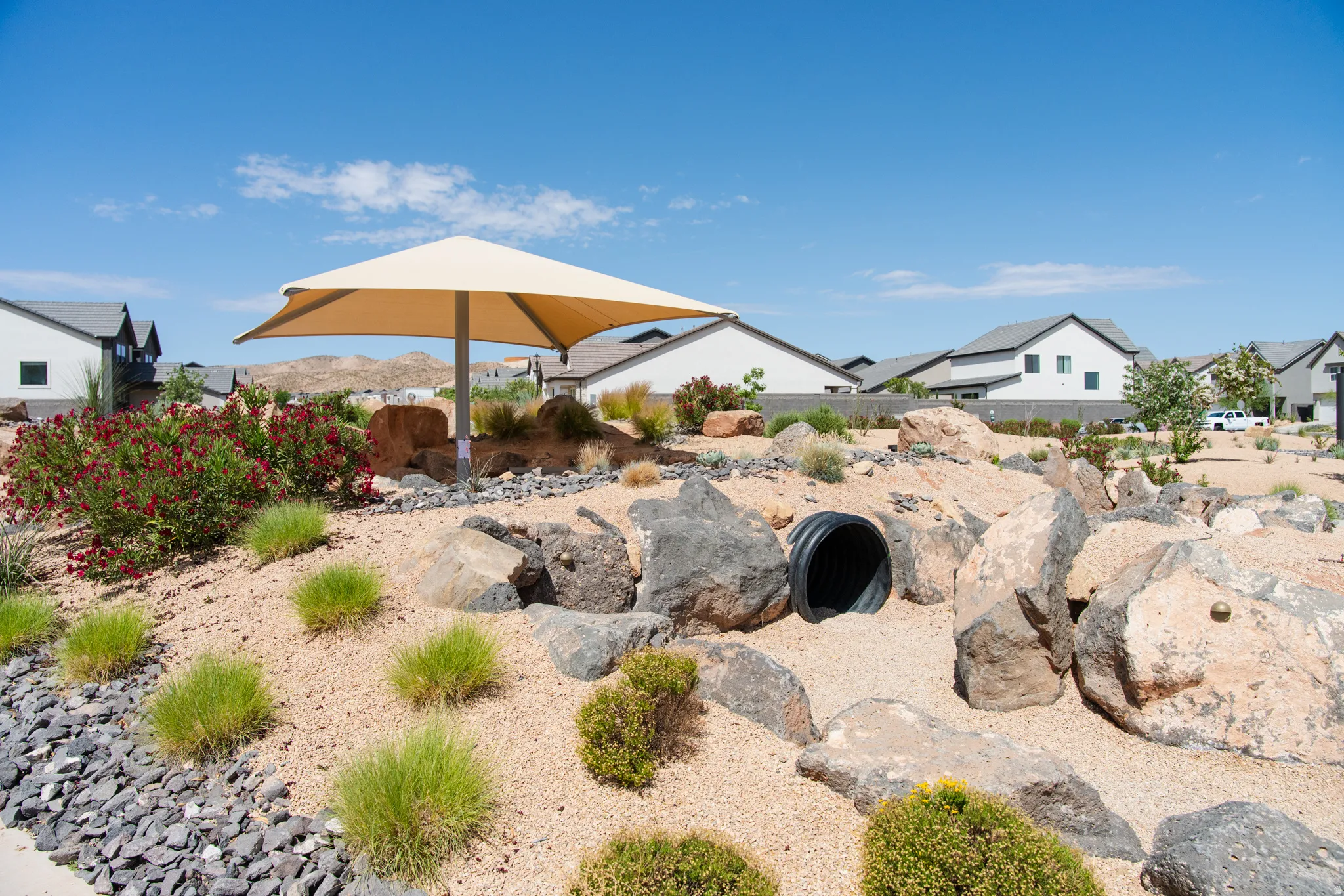 Outdoor space featuring desert landscaping with varied rock features, small shrubs, and a shade structure
