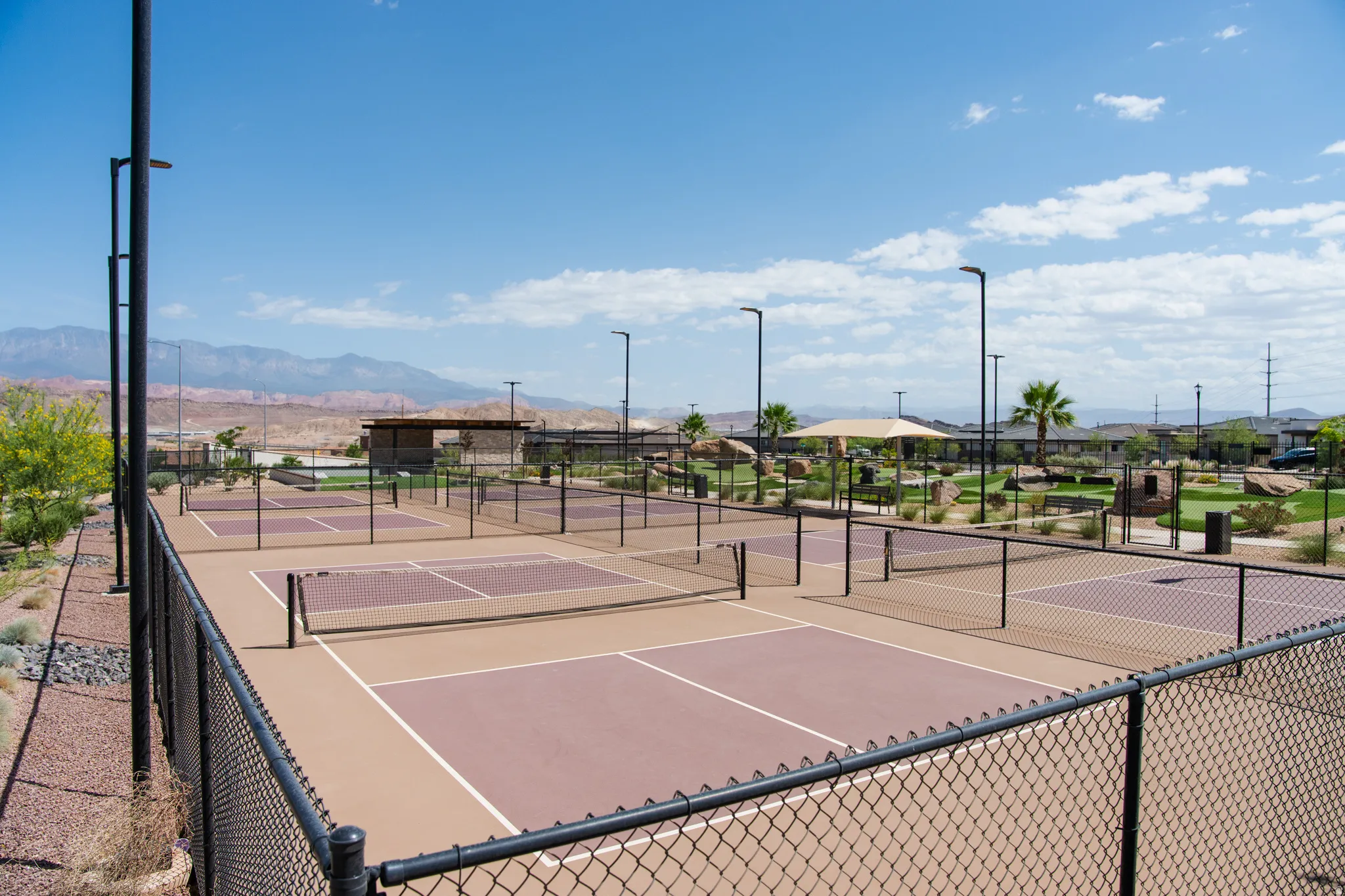 Multiple hard-surface courts with fencing and lighting