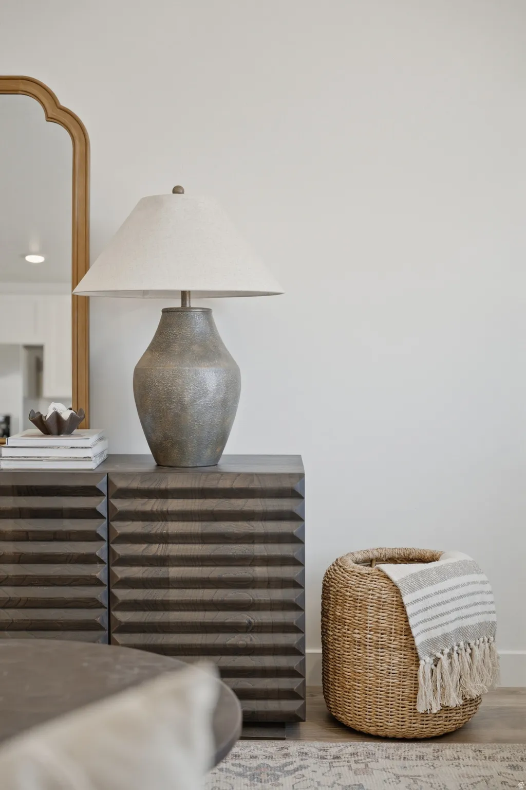 Accent wall featuring a gold-framed mirror and a textured wood-finish cabinet with horizontal detailing