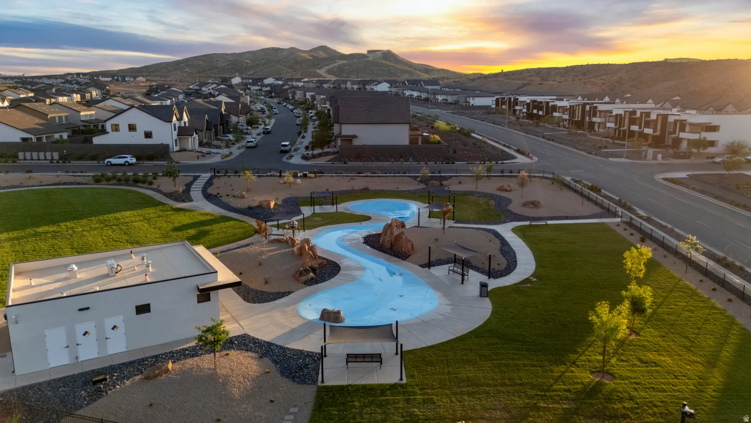 Community park featuring a splash pad, green spaces, paved pathways, and a modern utility building