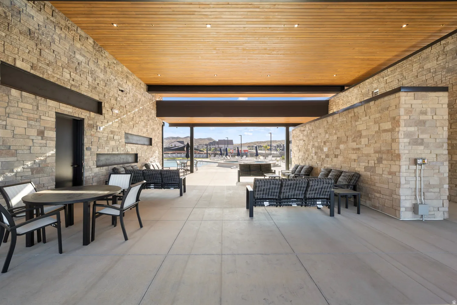 Expansive open-concept space featuring warm wood-finish ceiling with integrated recessed lighting, cream brick walls throughout, and polished concrete flooring