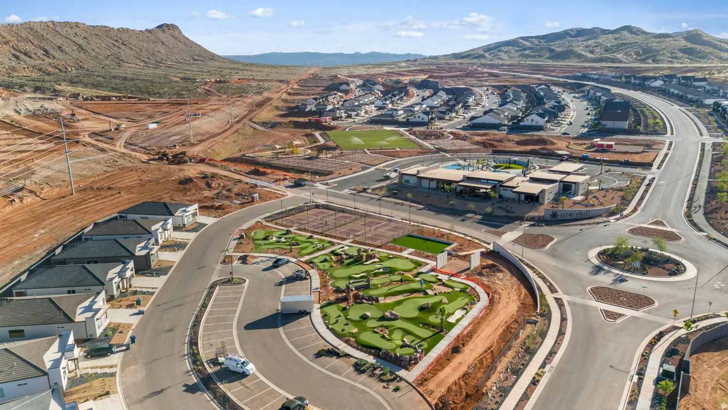Aerial view showcasing a newly developed residential community featuring multiple single-family homes with modern architectural design, curved street infrastructure, manicured green spaces, and strategic landscaping throughout the neighborhood