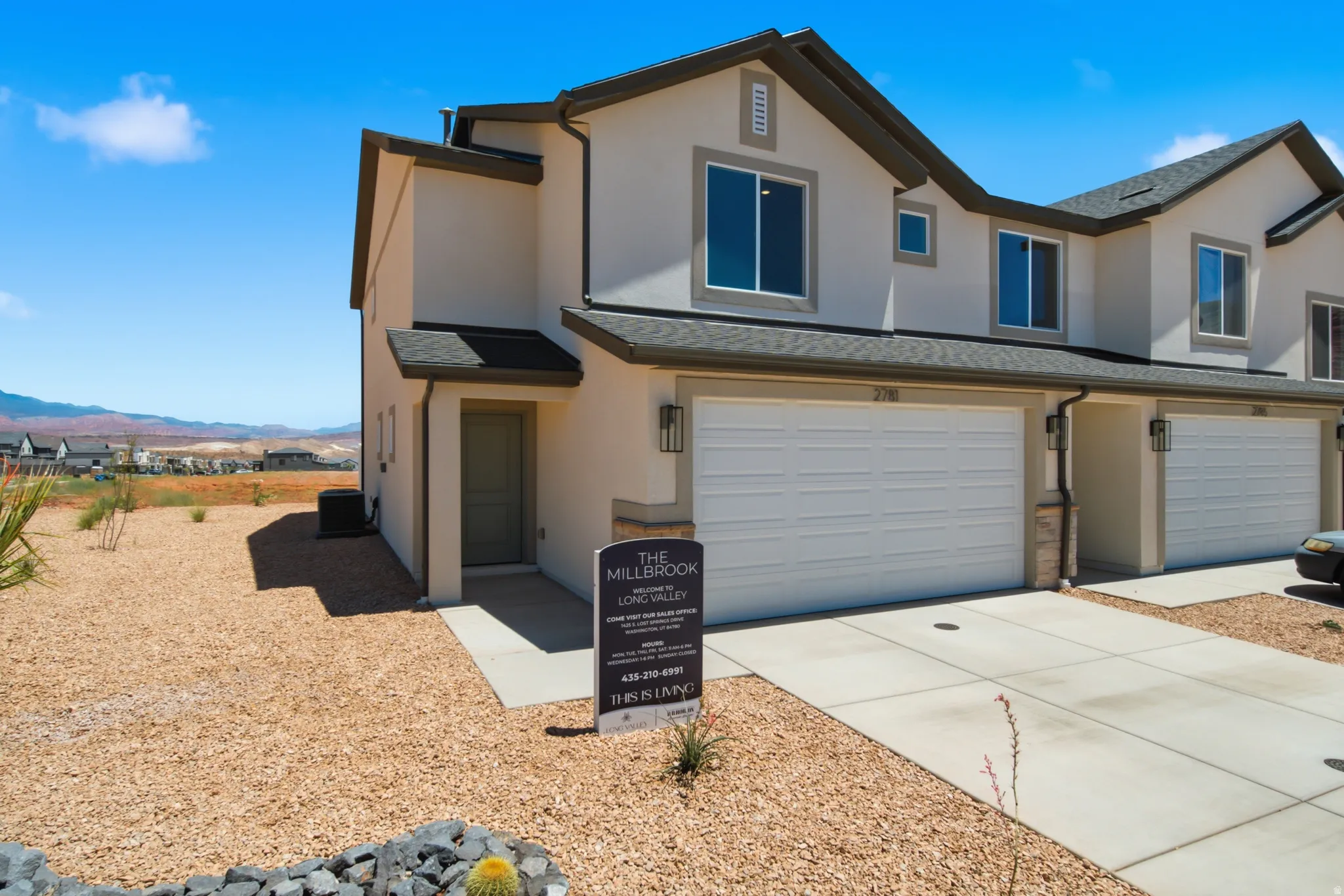 Contemporary multi-story residence featuring a two-car garage, light-toned stucco exterior, and dark-trimmed windows