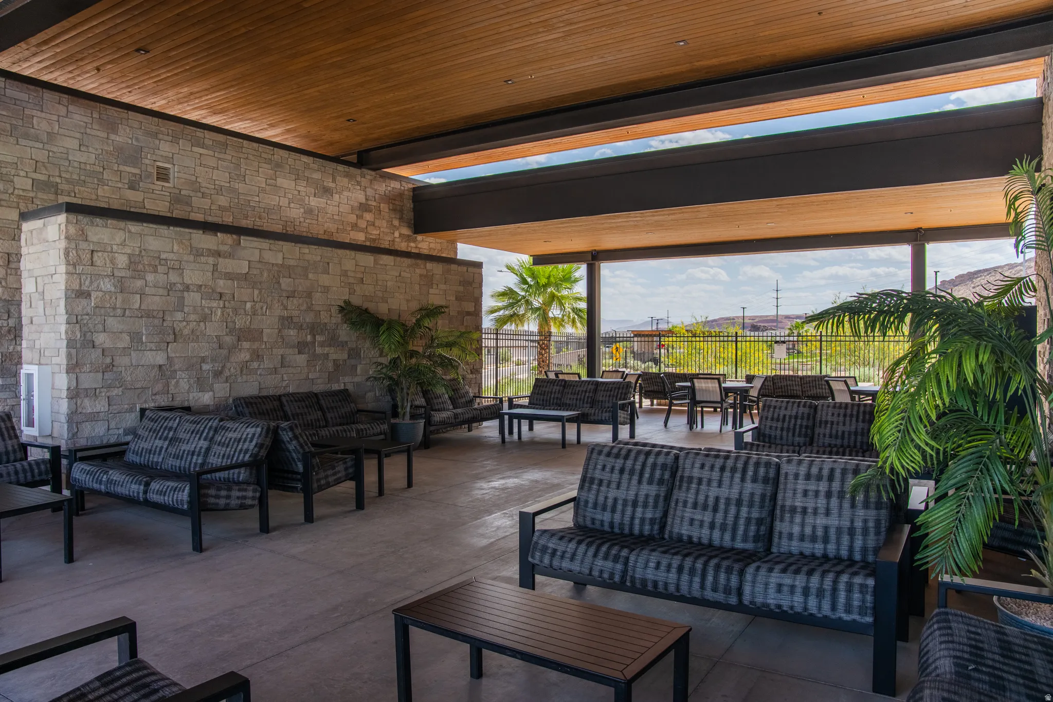 Covered outdoor patio featuring a stone-clad wall, wood-paneled ceiling, and open-air design