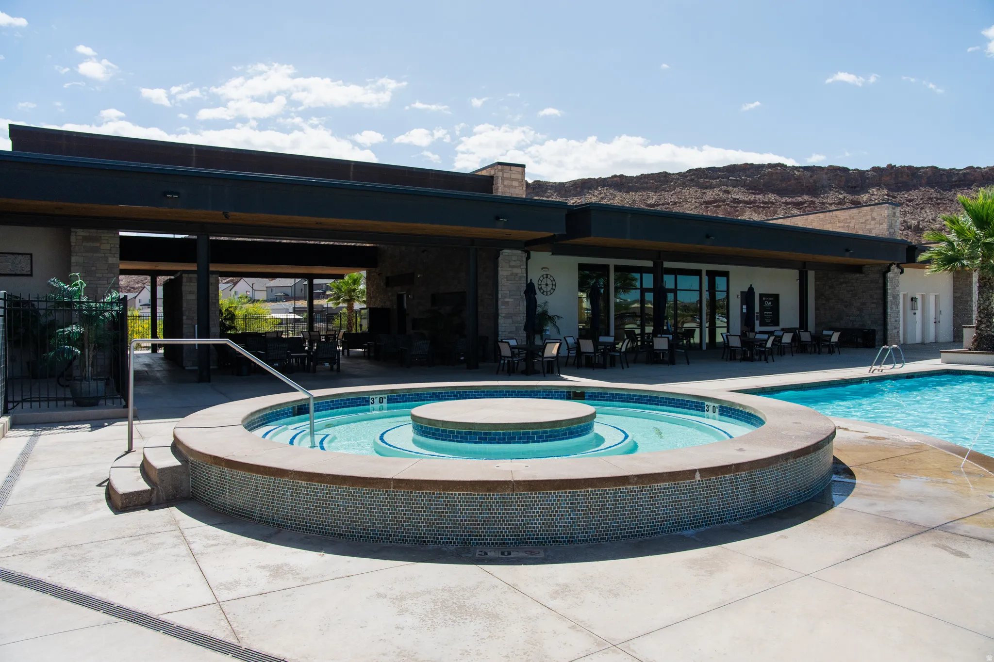 Resort-style outdoor living space featuring a circular spa with integrated seating, complemented by a zero-entry swimming pool with tanning ledge