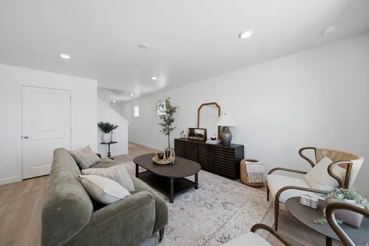 Open concept living space featuring recessed lighting, light wood-finish flooring, and a white interior door with panel detailing