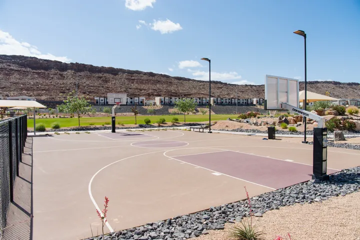 Outdoor basketball court featuring two hoops, court markings, and integrated lighting