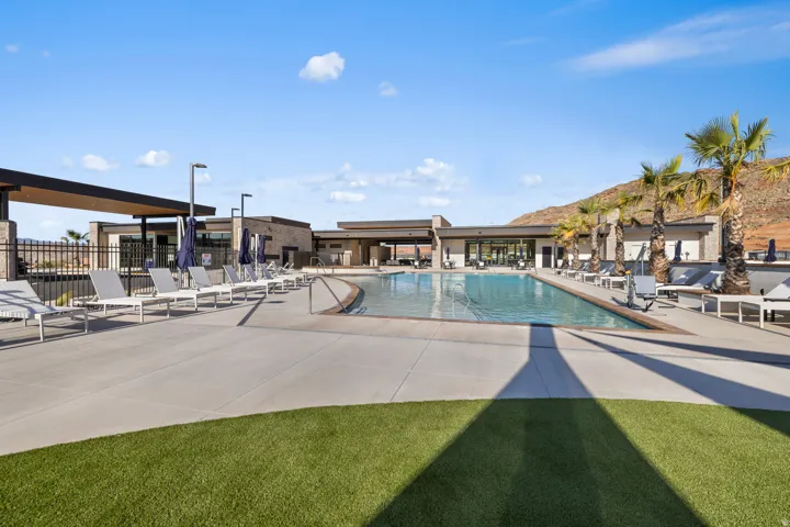 Expansive swimming pool with concrete decking, surrounding lounge areas, artificial turf accents, and desert mountain backdrop