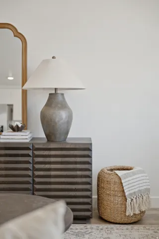 Accent wall featuring a gold-framed mirror and a textured wood-finish cabinet with horizontal detailing