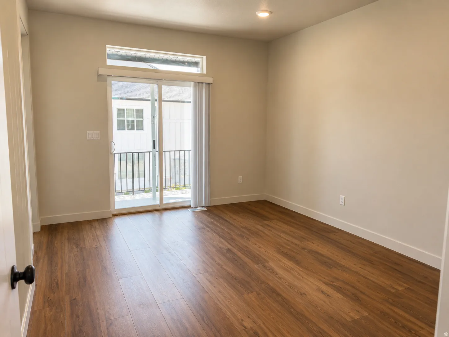 Spacious room featuring wood-finish flooring, neutral-toned walls, and a recessed ceiling light