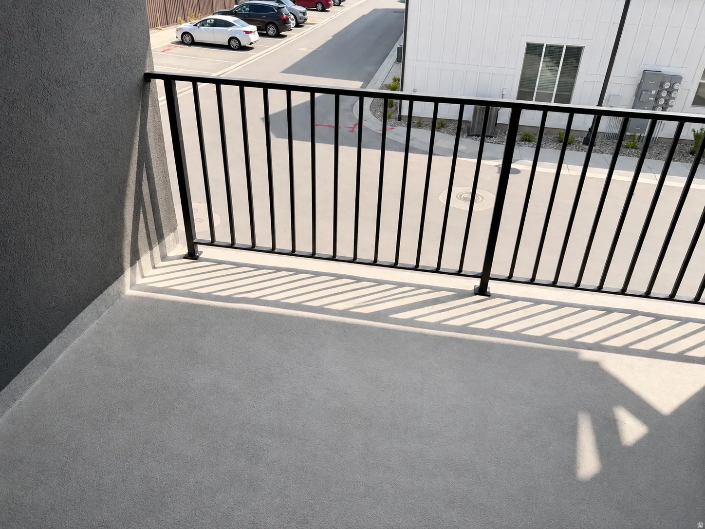 Private balcony with textured flooring and a black metal railing