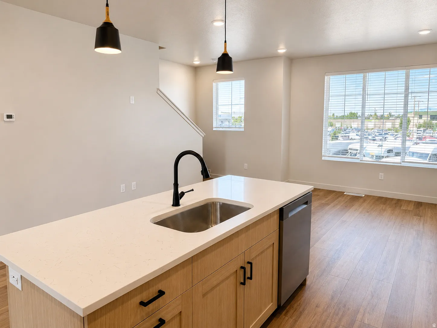 Modern kitchen island featuring white quartz countertops, a stainless steel undermount sink, and matte black gooseneck faucet