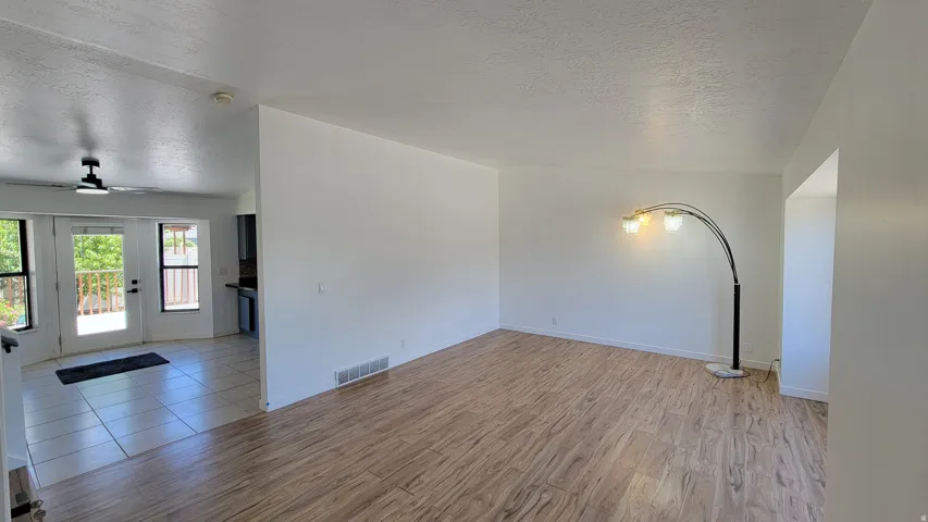 Wood-finish flooring, white painted walls, and ceiling-mounted fan in the tiled area