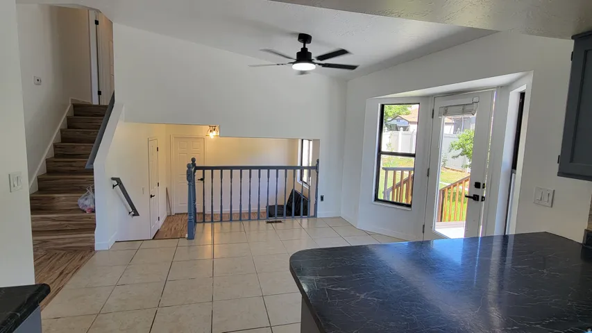 Vaulted ceiling with a ceiling fan, tiled flooring, wood-finish stairs, and French doors