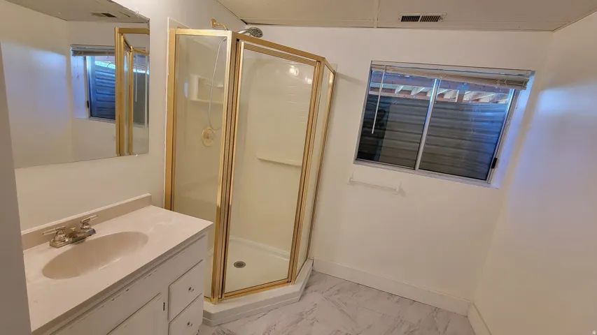 Corner shower with brass-finish frame and clear glass enclosure