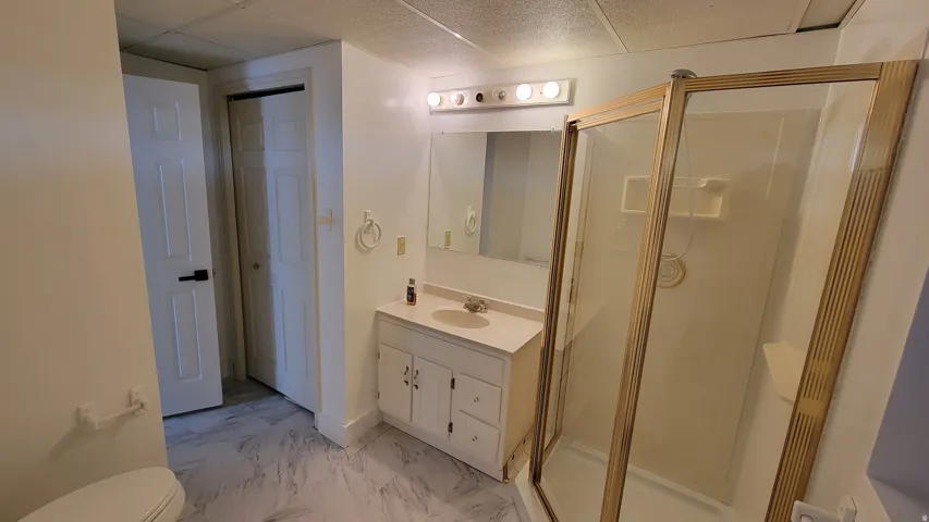White vanity with a single basin sink, wall-mounted mirror, and overhead lighting
