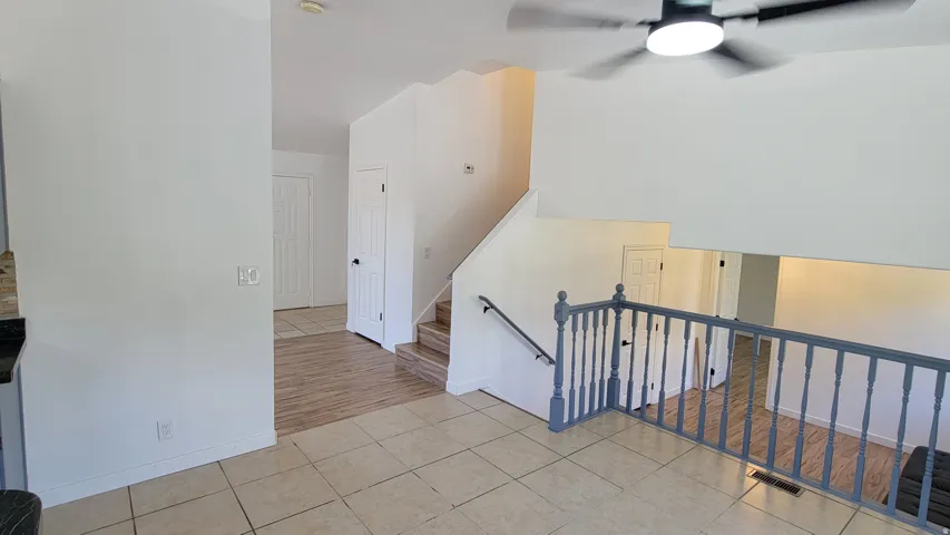Tile flooring, wood-finish flooring, staircase with railing, ceiling fan with integrated lighting, and multiple panel doors