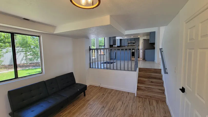 Recessed lighting, wood-finish flooring, staircase with wood-finish treads, painted railing, and a window with a black frame