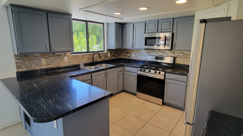 Kitchen featuring a stainless steel range, built-in microwave, grey cabinetry, and a black patterned countertop