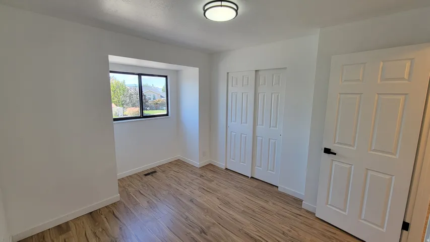 Wood-finish flooring, white walls, and a window with black trim