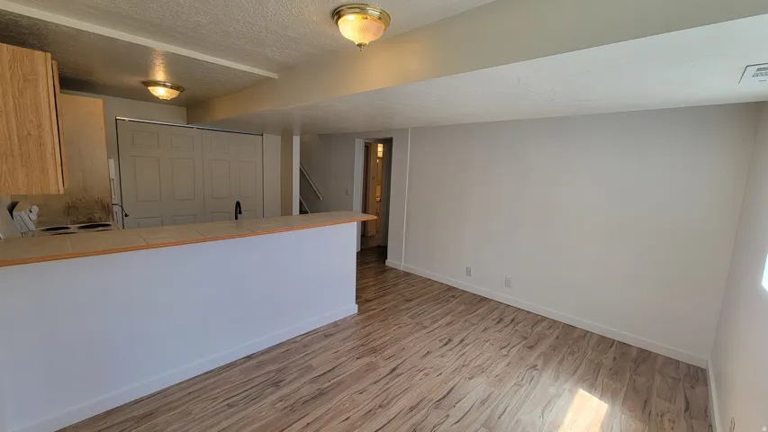 Open-concept space featuring wood-finish flooring, a kitchen with wood-finish cabinetry, and a breakfast bar with a tiled countertop