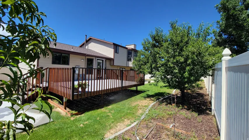 Spacious outdoor deck with wood railing, leading to a manicured lawn area