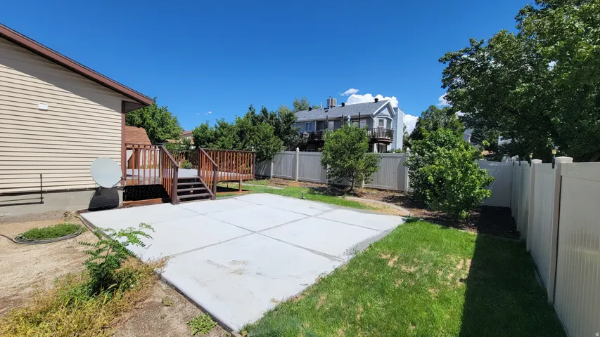 Expansive concrete patio with a wood deck and railing