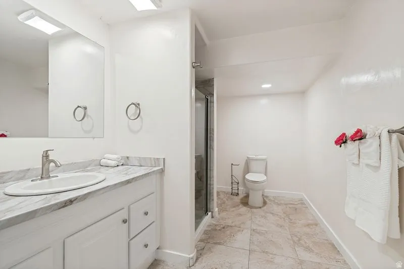 Bathroom vanity featuring a white oval undermount sink, brushed nickel faucet, and a marble-look countertop