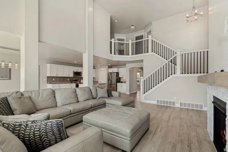Open-concept living space featuring a two-story foyer with curved staircase, white metal railings, and recessed lighting