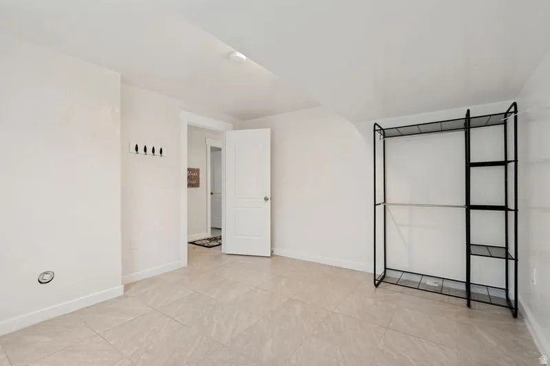 Spacious room featuring light-toned tile flooring, white walls, and a white ceiling