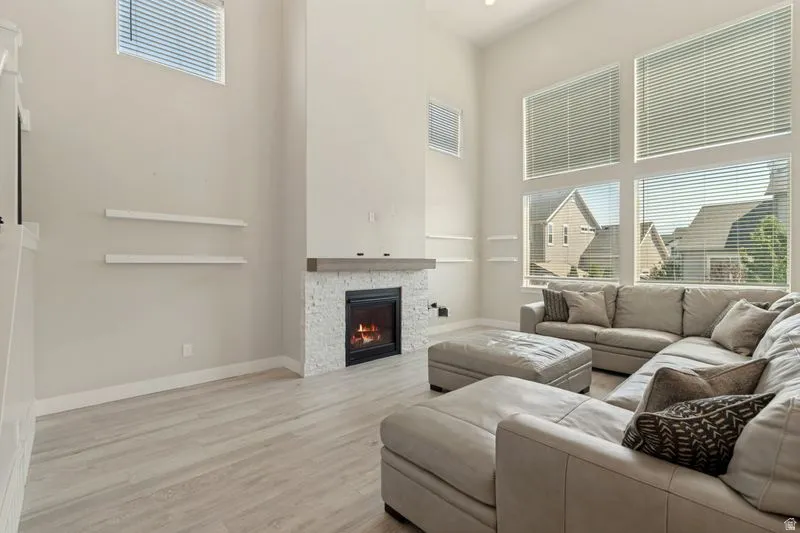 Spacious living area featuring a two-story ceiling, a multi-pane window wall, and light wood-finish flooring