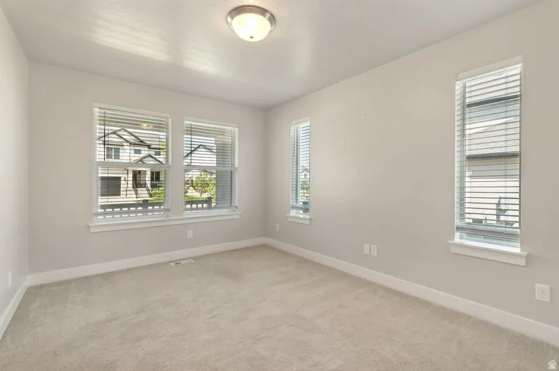 Bright and spacious bedroom flooded with natural light through multiple windows featuring plantation shutters