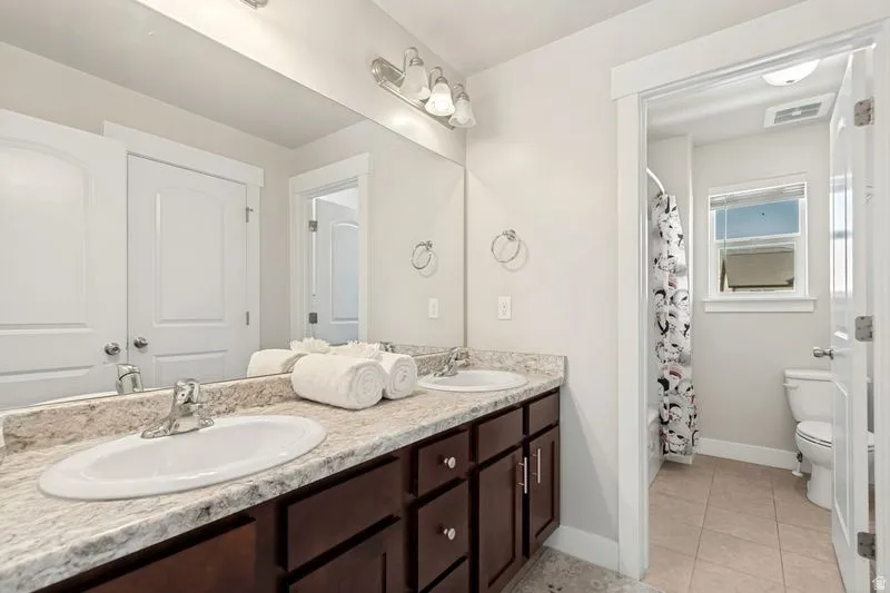 Bathroom featuring a double vanity with dark wood cabinetry, light-toned countertop, and integrated sinks