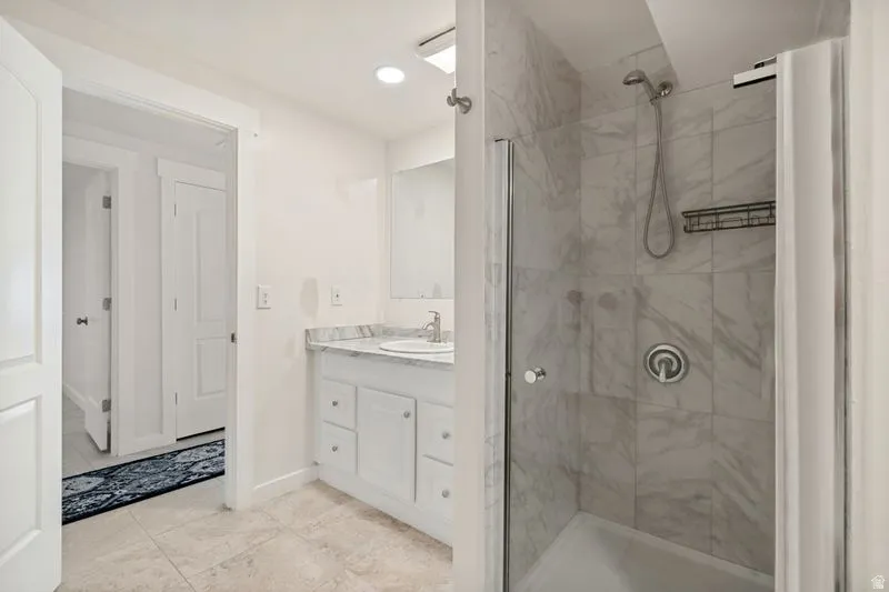 Spa-inspired primary bathroom featuring a walk-in shower with marble-look tile surround, rainfall showerhead, and built-in niche shelving