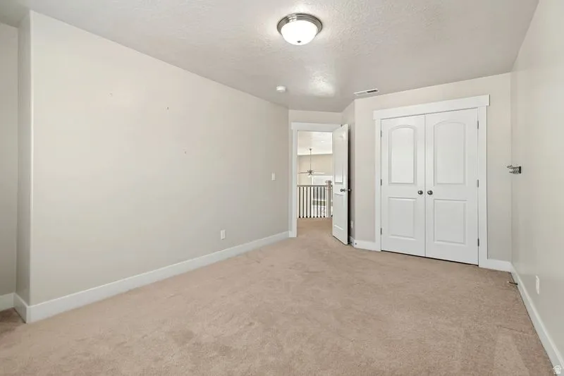 Carpeted room with neutral wall tones, white baseboards, and a semi-flush mount ceiling light fixture