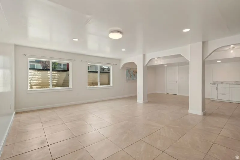 Spacious open-concept living area featuring neutral tile flooring throughout, recessed ceiling lighting, and multiple windows providing natural light