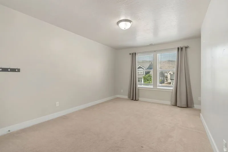 Bright room featuring neutral carpeting, light-toned wall paint, and white baseboards