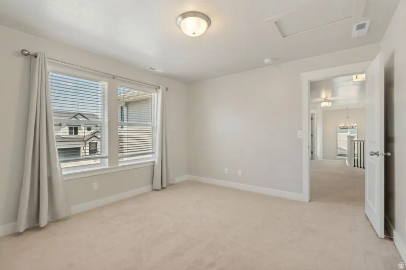 Carpeted room featuring a double window with blinds and drapes, an overhead flush-mount light fixture, and white baseboards