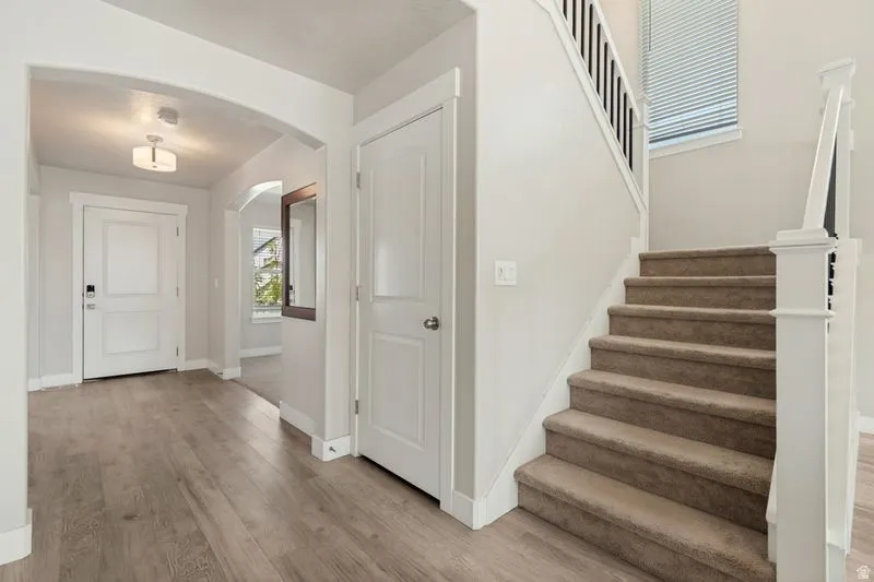 Entryway featuring wood-finish flooring, an arched doorway, and a contemporary flush-mount light fixture