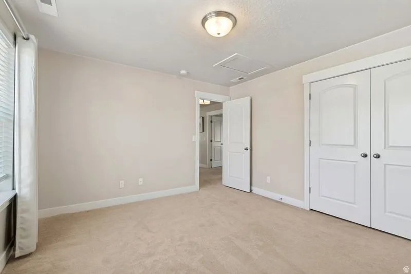 Spacious bedroom featuring neutral wall finishes, neutral carpet flooring, recessed ceiling lighting, and dual closets with six-panel doors