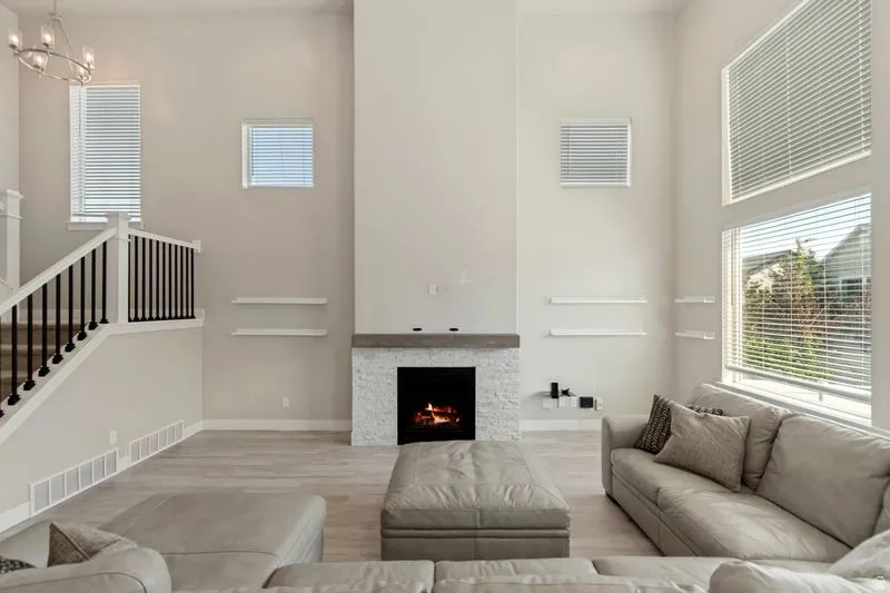 Soaring two-story living space anchored by a striking linear fireplace with stone surround and modern black mantel