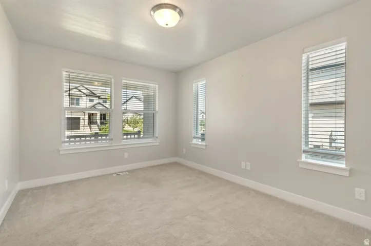 Bright and spacious bedroom flooded with natural light through multiple windows featuring plantation shutters